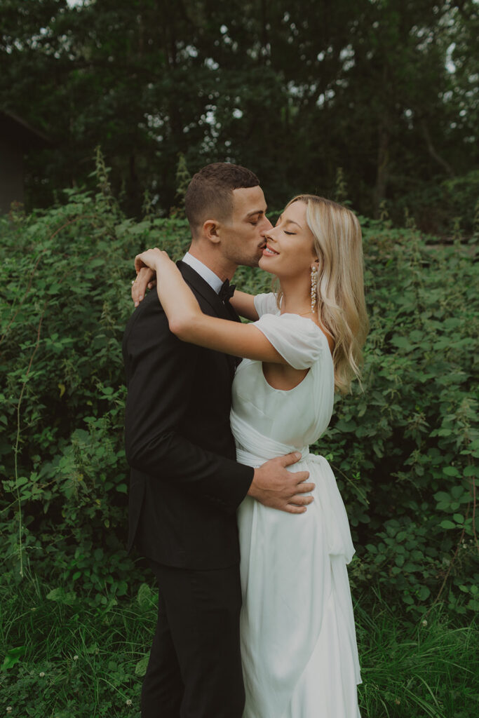 man kissing a woman on the cheek in paris in a green forest
